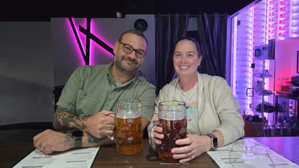 Scott and Gerrie smiling behind two giant steins of beer