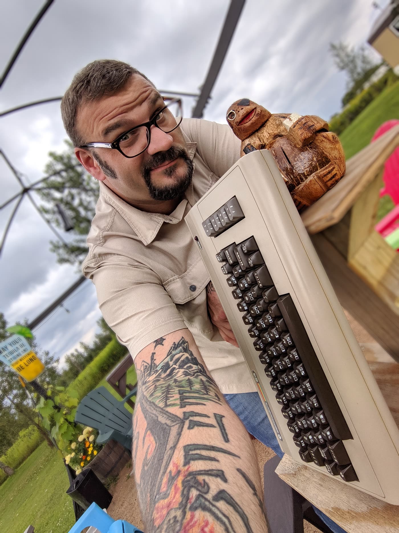 Scott holding up an old Commodore 64 computer, with a carved wooden bird on top of it