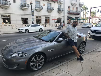 Scott leaning against a gray Jaguar convertible on a street in St. Augustine