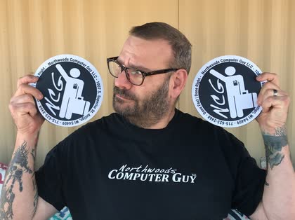 Scott holding up two round Northwoods Computer Guy mouse pads next to his face