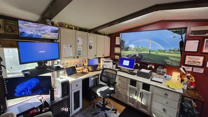 The inside of Scott's office: a long desk with several monitors, laptops and equipment under a wood-beam ceiling