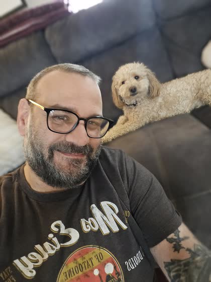 Scott smiling with Teddy resting on the couch behind him