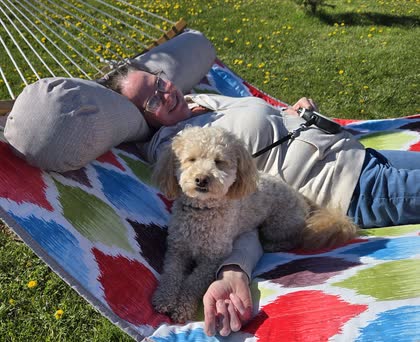 Teddy lying on a colorful hammock next to Gerrie, who is resting her head on a pillow